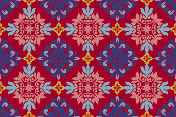 Fototapeta premium ikat seamless vector pattern featuring symmetrical floral motifs in vibrant red, blue, pink, and gold tones. Decorative ethnic ornament design with repeating geometric elements