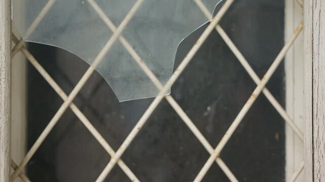 Close up detail of shattered glass attached to a metal wire fence with shallow depth of field