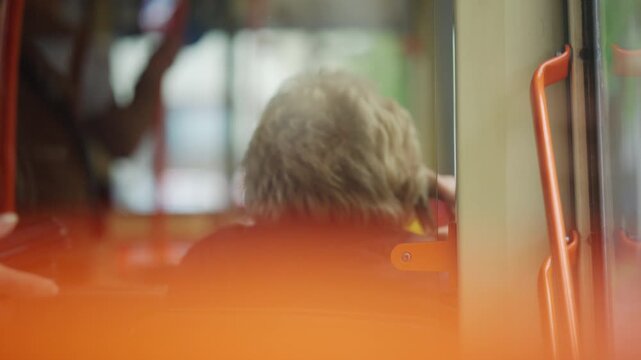 Soft focus interior view of a passenger sitting inside a public transportation vehicle