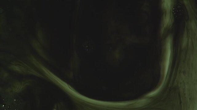 Abstract background of dark green and black ink swirling underwater. Mesmerizing fluid motion creates a moody, smoky organic pattern. Perfect for dramatic overlays.