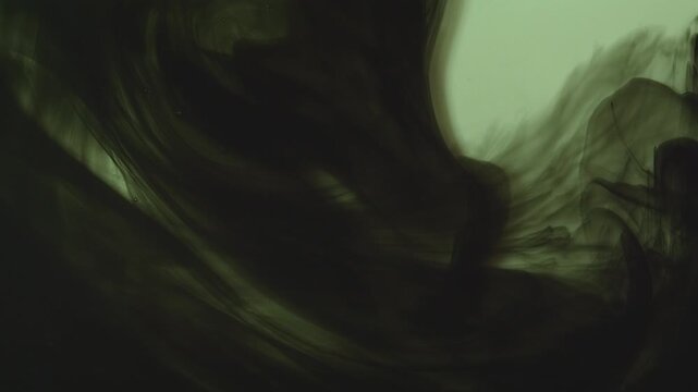 Abstract background of dark green and black ink swirling underwater. Mesmerizing fluid motion creates a moody, smoky organic pattern. Perfect for dramatic overlays.