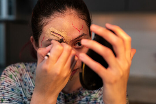 Redhead model detailing red veins near her eye with a mirror in hand at home