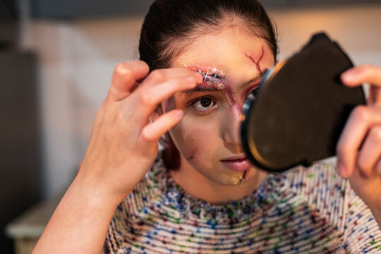 Distressed character touching a stapled forehead wound during Halloween makeup