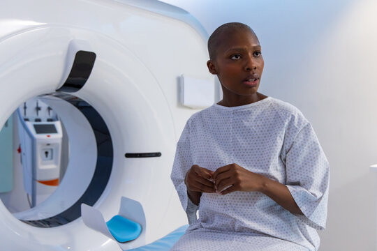 African female patient sitting on scan table beside imaging gantry with blue headrest, copy space