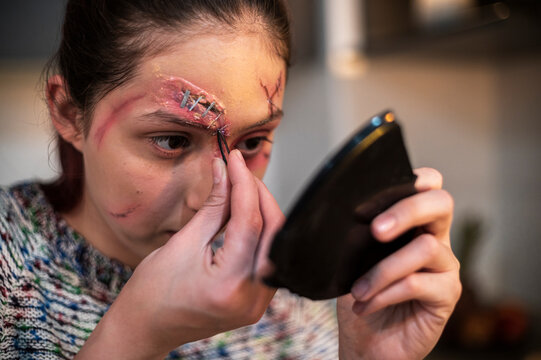 Redhead model blending an eye wound with her fingers while holding a phone