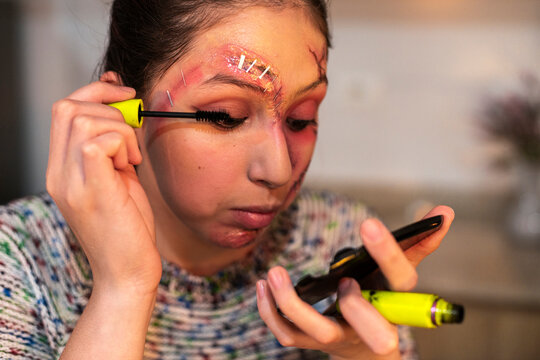 Close up of woman applying mascara over gruesome special effects wound makeup