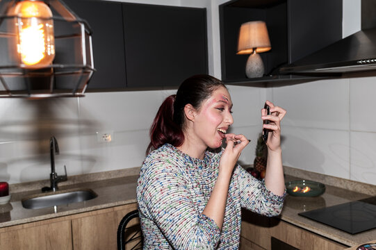 Redhead character finishing her Halloween makeup standing in a lamplit kitchen