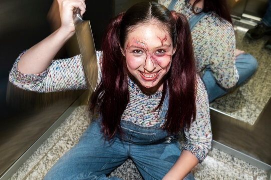 Crouching killer doll character grinning with a knife under harsh elevator flash