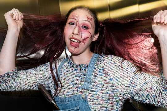 Menacing costumed character with red pigtails and fake blood holding a kitchen knife