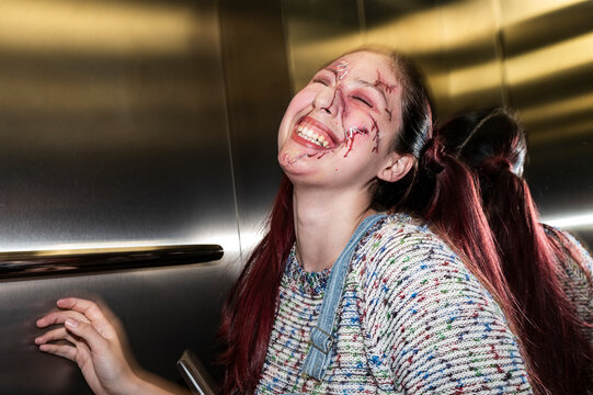 Bloodied character laughing maniacally under direct flash in a mirrored elevator