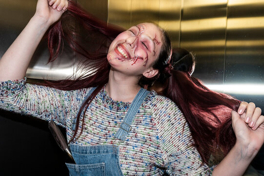 Playful menacing doll character with red pigtails posing in a steel elevator