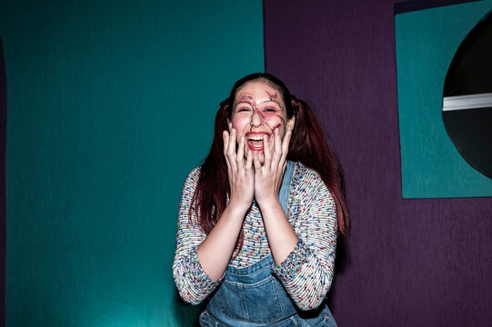 Screaming costumed character clutching her face against a teal studio wall