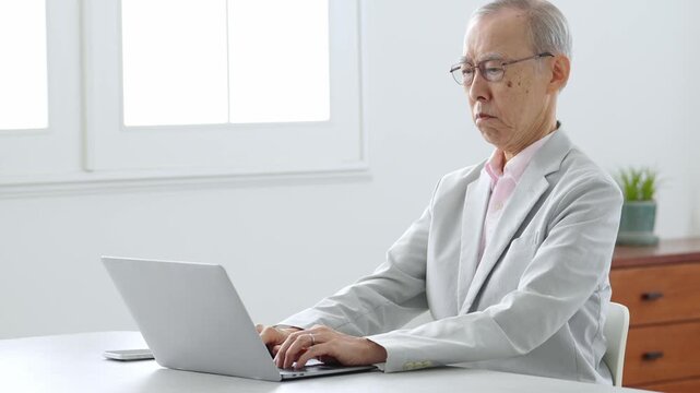 困った表情でパソコンを使う高齢者の男性