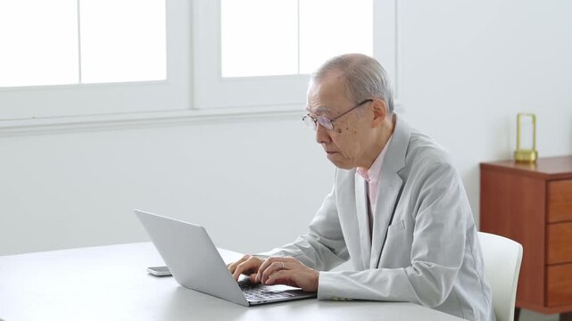 困った表情でパソコンを使う高齢者の男性