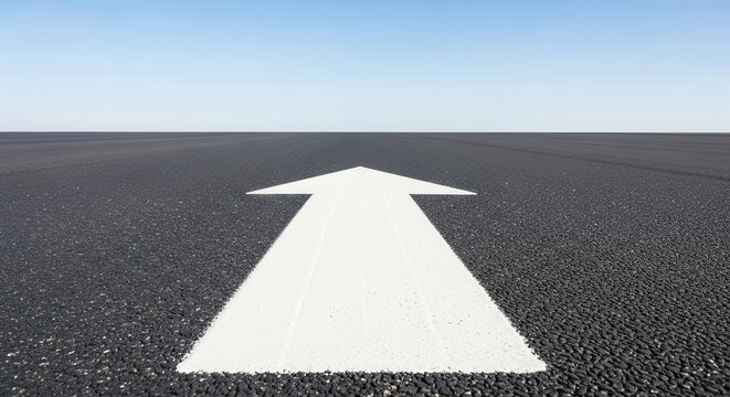 A low angle view of a crisp white directional arrow painted on a dark grey asphalt road surface pointing forward toward a clear horizon, journey, ground, line