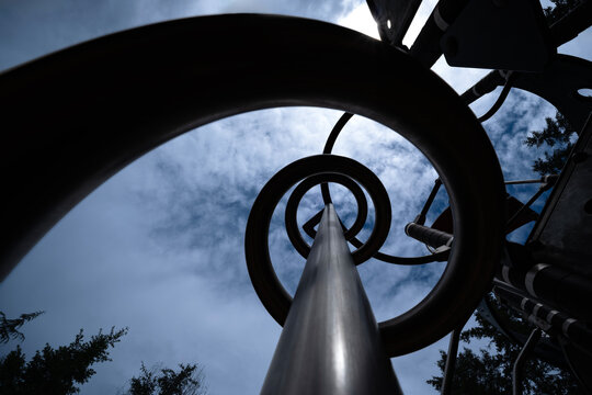 Metal spiral structure in playground against dramatic sky