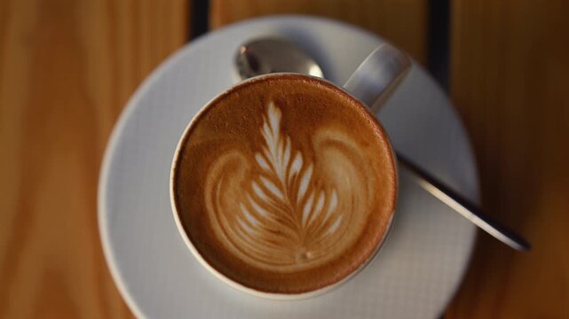 Freshly prepared latte served in a ceramic cup with elegant leaf shaped latte art on creamy foam