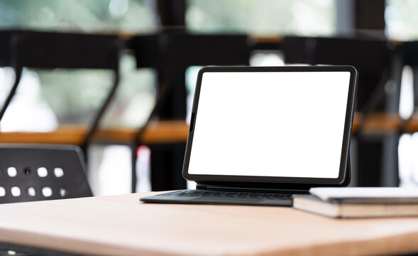 Digital tablet mockup with blank white screen on wooden table in cafe.