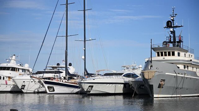 Collection of luxury yachts and motorboats moored side by side in a the Cannes marina under clear blue skies