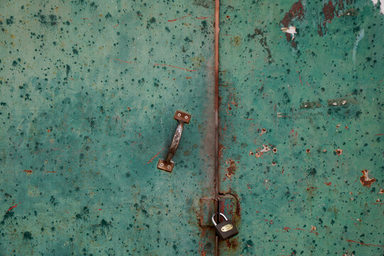 Rusty green door with lock and handle showing aged texture