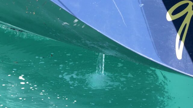 Bilge Pump Water Discharging from Blue Yacht Hull into Turquoise Sea