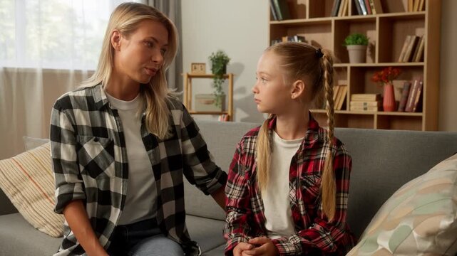 Family quarrel upset little Caucasian girl child cross arms ignoring mom at home argue offended daughter mother parent woman caring worried female touch schoolgirl kid speak talking apologize problem