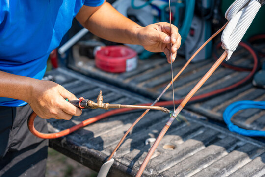 Technician man soldering and brazing copper pipes for air conditioning system installation, Professional HVAC worker using blow torch to join copper tubing on a pickup truck bed