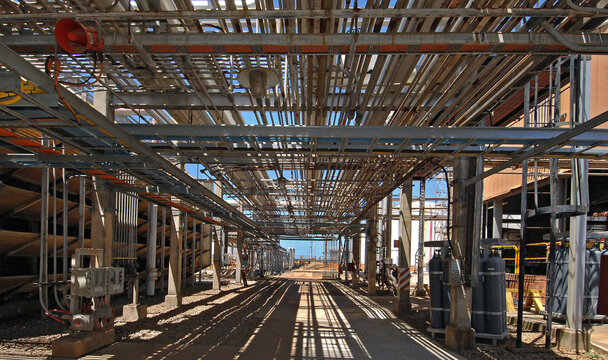 The technically complicated walkways that traverse through a gas refinery covered in wiring and pipes