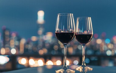 Obraz premium Wine glasses with red drink on urban city bokeh lights romantic evening celebration luxury