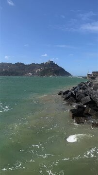 Vertical shot of Bah&iacute;a de la Concha with rough seas and Monte Igueldo backdrop sunny day. Donosti, San Sebasti&aacute;n