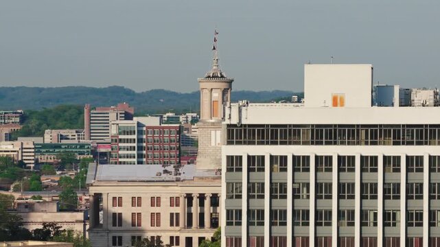 Aerial drone view of the Tennessee State Capitol building at dusk in Nashville, with its classical cupola, green copper roof, and surrounding cityscape below.