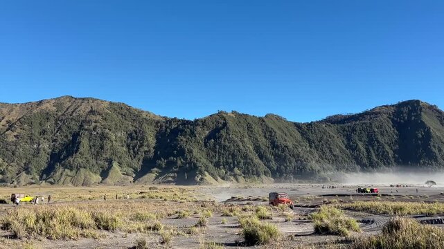 Majestic View of Mount Bromo Volcanic Desert Landscape with Vast Sand Plains and Rugged Mountain Ranges Under a Clear Blue Sky
