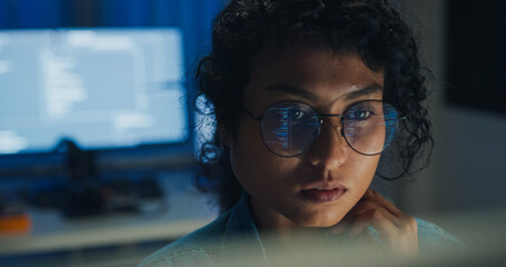 Close-up Black female programmer with code reflection in glasses working late in home office at night. Cybersecurity, AI algorithm, Network security, software developer, serious face, burnout concept.