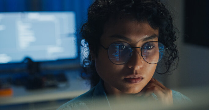 Close-up Black female programmer with code reflection in glasses working late in home office at night. Cybersecurity, AI algorithm, Network security, software developer, serious face, burnout concept.