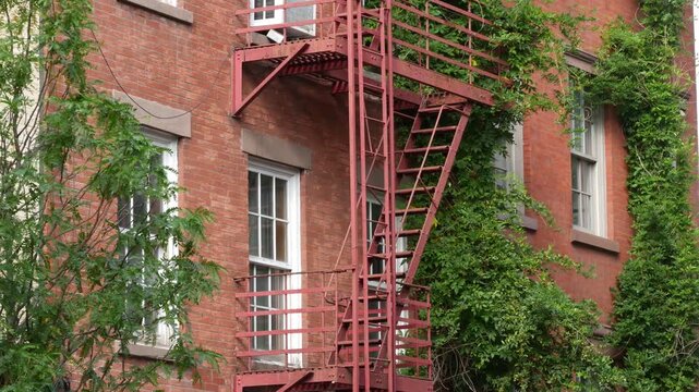 New York City urban residential buildings architecture, Manhattan classic street, United States of America. Typical red brick house in NYC, real estate property in USA. Fire escape metallic ladder.