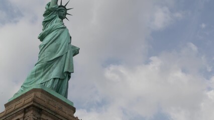 Fototapeta premium Statue of Liberty on Liberty Island, New York, United States. Blue cooper monument, symbol of democracy and patriotism near Manhattan, NYC USA. Clouds on sky. American independence. Torch and crown.