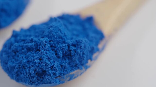 Blue powder on a wooden spoon in a bright setting