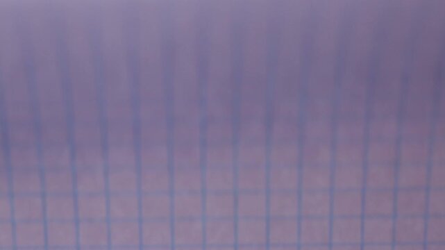 Flipping through the pages of a gridded notebook, paper background