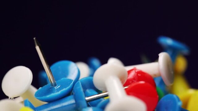Stationery, many push pins of different colors rotating on a black background