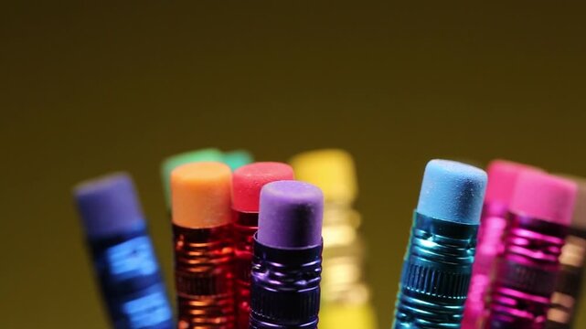 Stationery, many pencils of different colors with erasers facing up on a yellow background