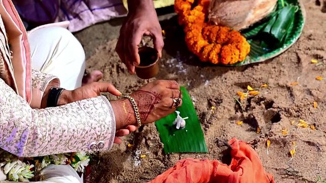 Close-up footage of bride and groom hands participating in traditional Hindu wedding rituals during a marriage ceremony in India. The scene captures sacred customs, ceremonial offerings
