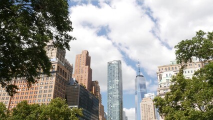 Fototapeta premium New York City Manhattan Downtown Financial District, United States of America. World Trade Center skyscraper, tower building in FiDi. Modern business center from Battery park. Summer tree greenery.
