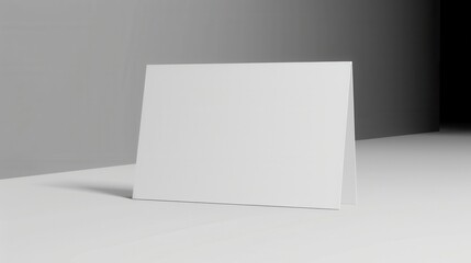 Naklejka premium Blank white paper card standing on table, minimalist interior background.