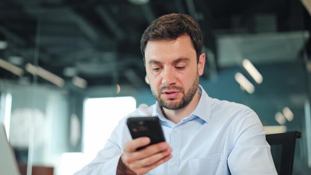 Close-up of businessman or IT specialist dictating audio note on cellphone. Corporate worker, manager or freelance designer recording voice message at contemporary coworking workspace desk.