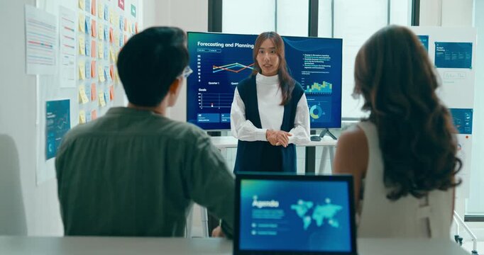 Group of Asian businesspeople work together leads business meeting uses presentation TV with revenue, profit or sale statistics in office. Financial generation z team brainstorm on e-Commerce project.