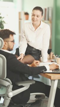 Female employee sitting on a table in a miniskirt and trying to seduce male boss during the working day. European woman flirting with work colleague. High quality 4k footage