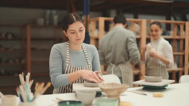 Young woman pottery workshop workers sculpt from raw clay. High quality 4k footage