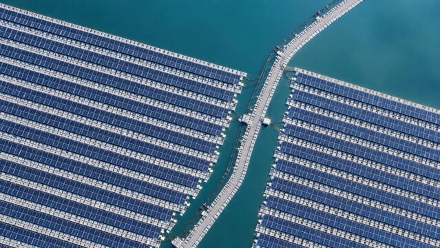 Solar panels are arranged over water with a walkway connecting installations during daylight hours in an energy generation area