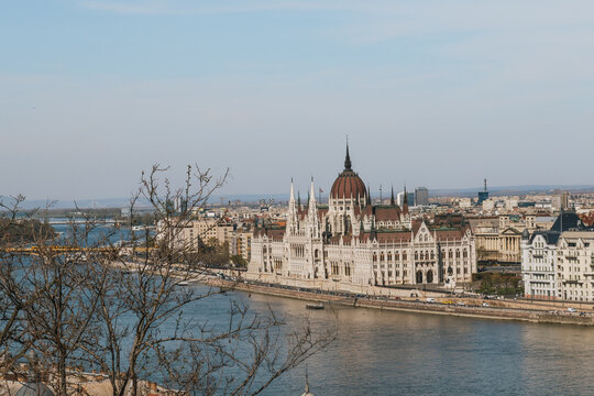 Gothic revival palace framed by green spring foliage along a scenic European river