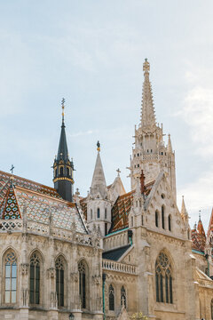 Ornate Gothic Revival church with colorful tiled roof and decorative stone towers